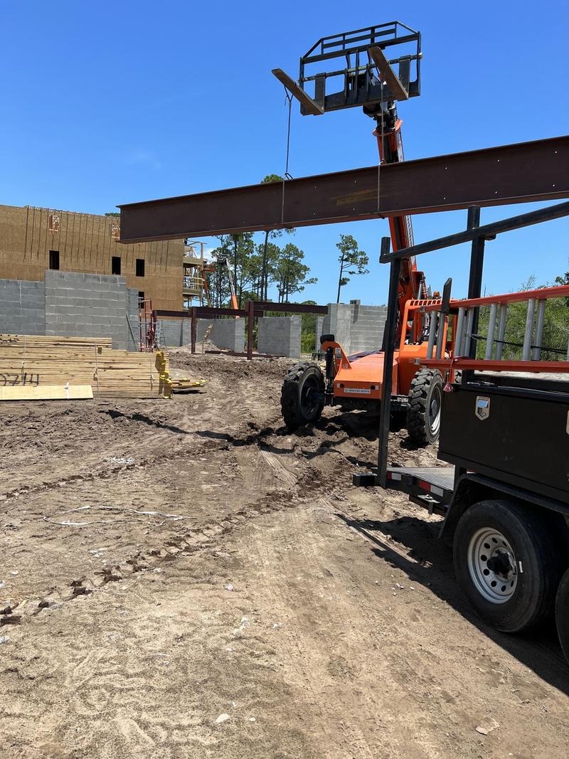 Griffis crew flying a steel beam into place with a telehandler